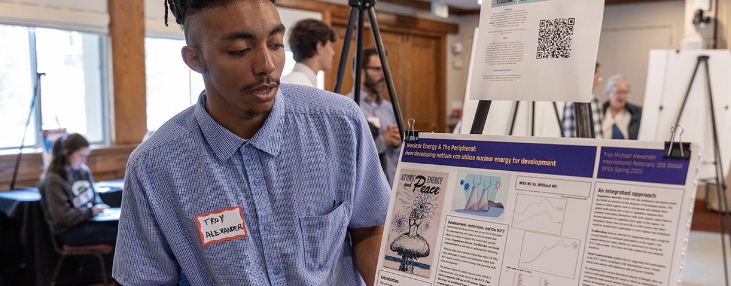 Person in a blue shirt looking at a poster board while they present the information.