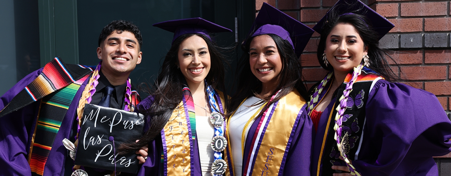 Four people in graduation attire smiling.
