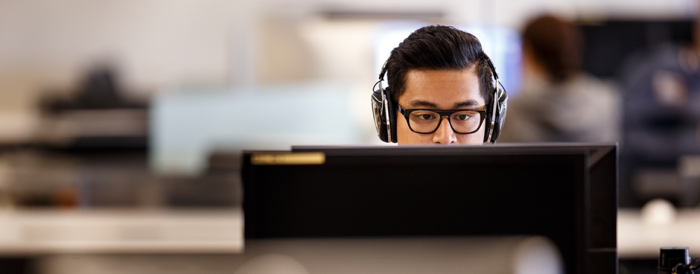 A student wearing headphones works on a computer