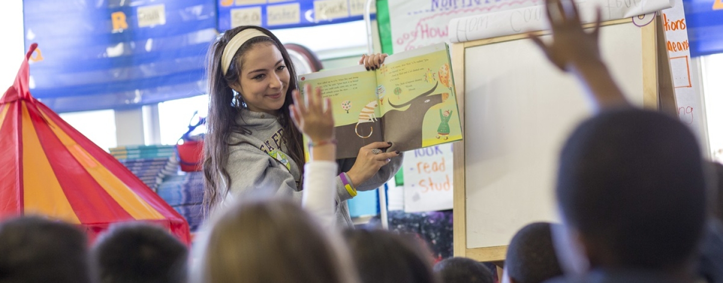 A student reads to children in a classroom