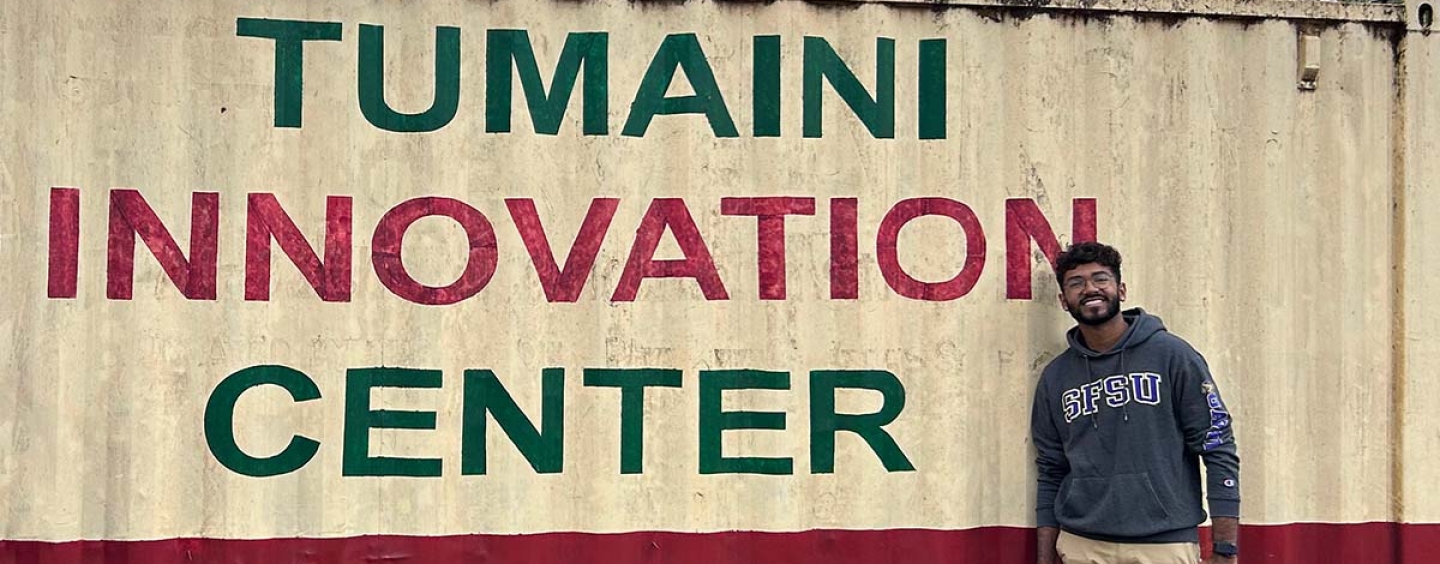 Vasav Juthani standing by Tumaini Innovation Center sign