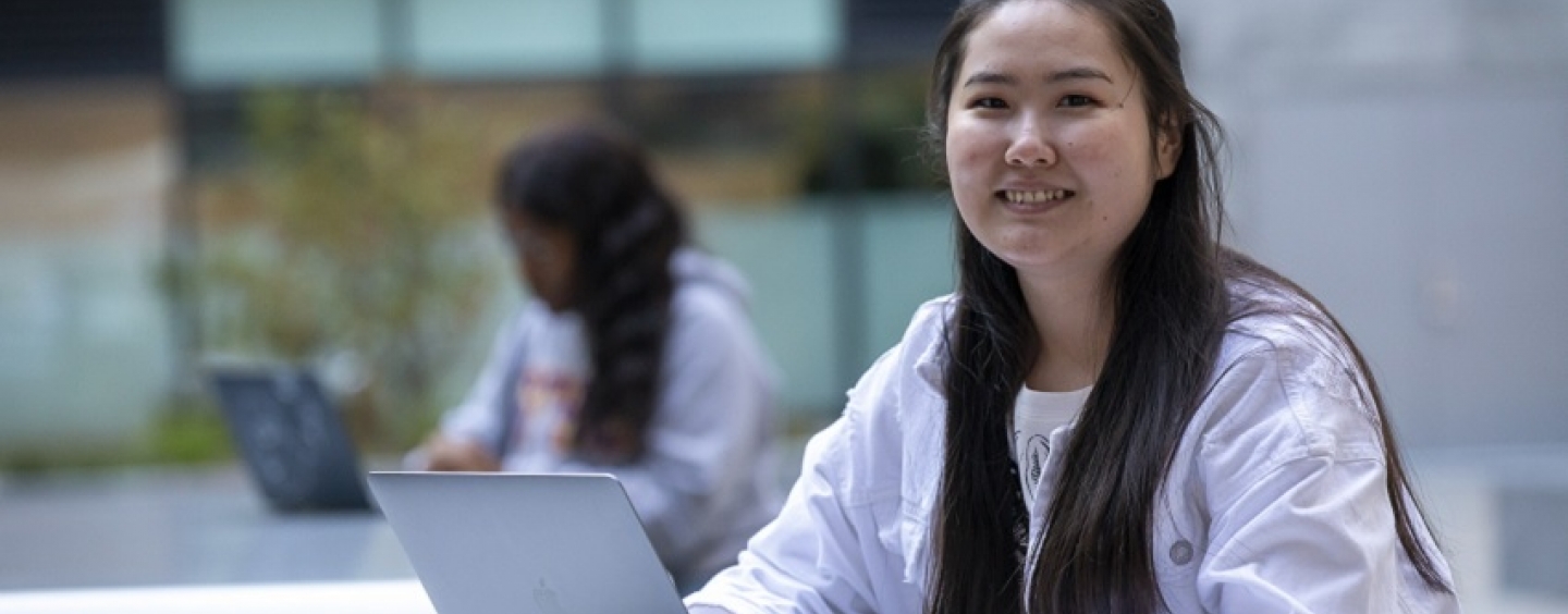 A female student smiles as she works on her laptop