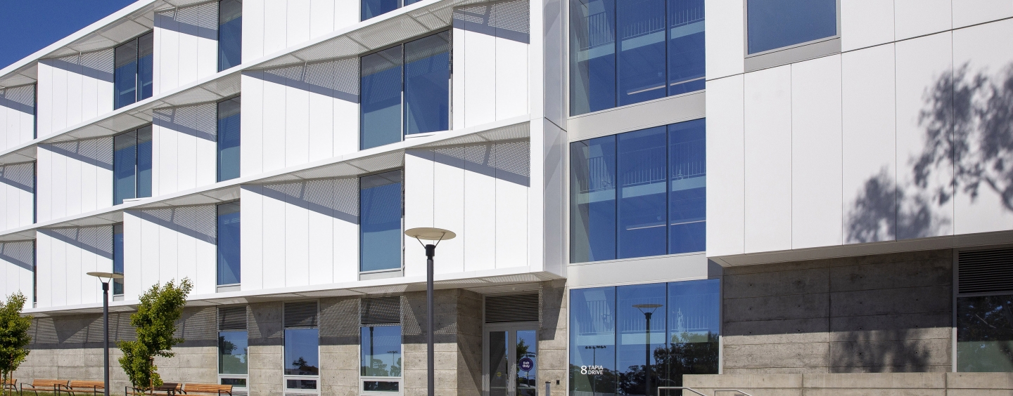 White and gray building with grass in front of it.