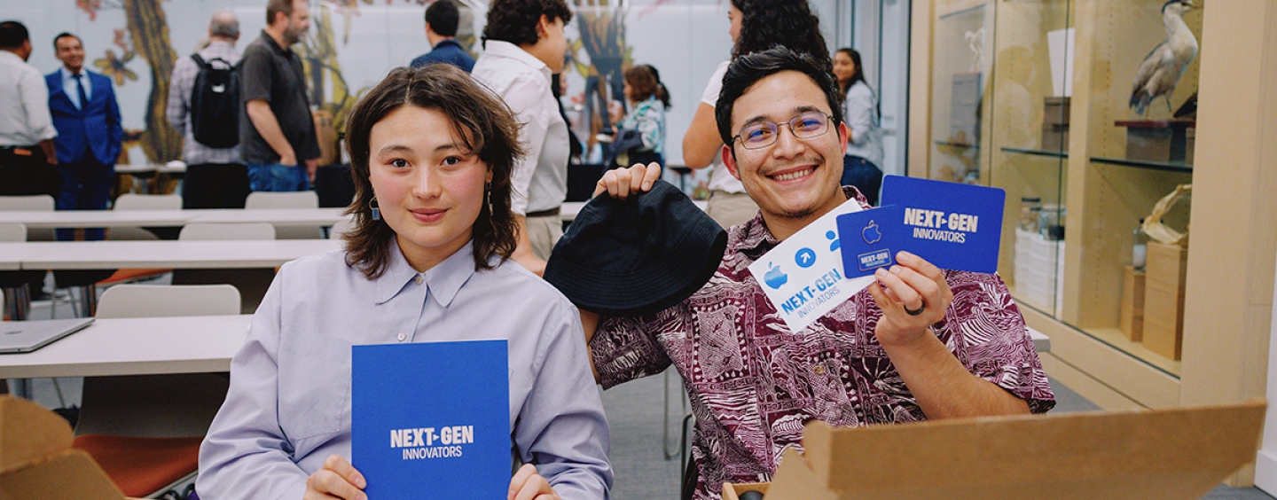 Two students smiling and holding Next-Gen mentorship program booklets