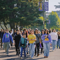 A student tour guide leads future SFSU students and families on a walk through the Quad on a sunny day 