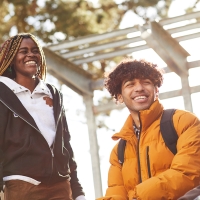 Three smiling students hanging out with each other in a group.