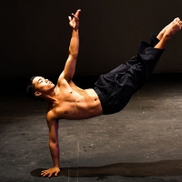 Johan Casal balances himself on his right hand while lifting his right arm and legs in the air while dancing in a studio
