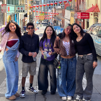 Five students pose for a photo while standing in a street in the Chinatown neighborhood of San Francisco on a sunny day