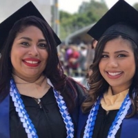 Christina and her sister pose for a photo in commencement regalia 