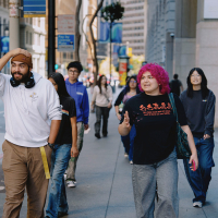 A group of students walk on a street in downtown San Francisco on a sunny day