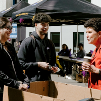 SF State President Lynn Mahoney (right) speaks with a family in front of the newly built West Grove Commons residence hall. Photo by Kevin Perez.