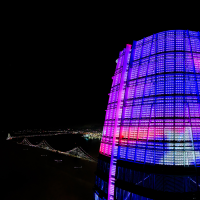 A drone photo of the top of the Salesforce Tower in San Francisco showing colorful SFSU student artwork with the Bay Bridge visible in the background