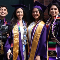 Four people in graduation attire smiling.