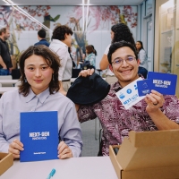 Two students smiling and holding Next-Gen mentorship program booklets